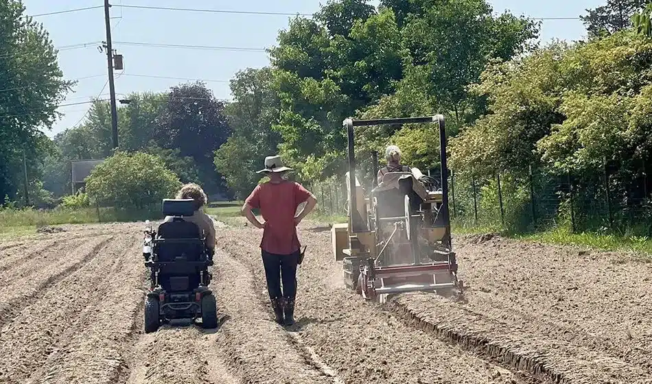 A farmer operating a tractor, while a person in a power wheelchair.