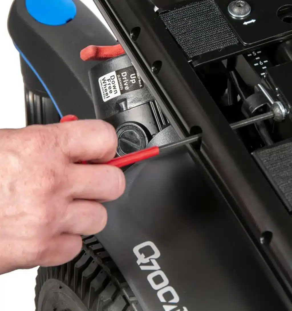 Q700M A person uses a red screwdriver to adjust a component on a Q700M power wheelchair.