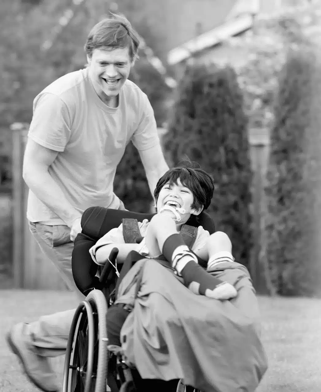 hero-img A person pushes a child in a wheelchair through a grassy area