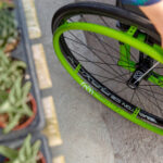 Neon green bicycle wheel and rim resting on a concrete path.